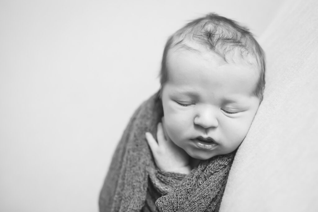 baby photographed by a newborn photographer in oklahoma city, swaddled and showing his newborn face