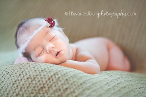 girl newborn 14 days old asleep on green blanket with little rose headband