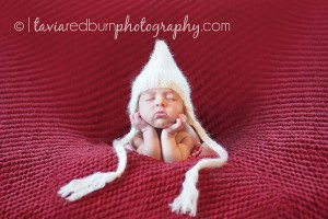 newborn baby girl with her head in her hands 14 days old with white hat