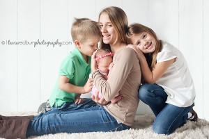 siblings holding their newborn sister