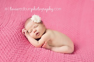 newborn baby girl posed on pink blanket