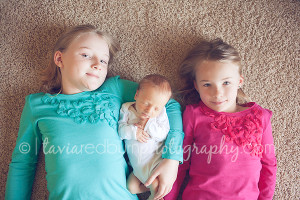big sisters with their newborn baby brother