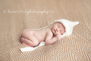 sleeping baby girl on brown blanket with white bonnet