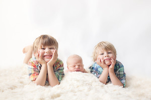 big brothers with their newborn baby brother pose