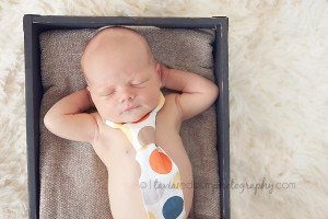 newborn baby boy with his hands behind his head with a tie