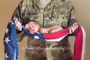 newborn dad holding baby girl in US flag, flag pose, military