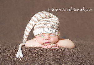 posed newborn with simple neutral colored hat, head on hands