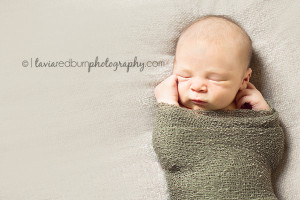 wrapped newborn baby boy, swaddled in army green