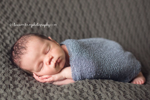 newborn pose, hands flat wrapped in blue swaddle