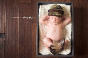 cute newborn pose with camo hat and cowboy boots
