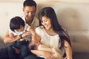 family laughing and playing with newborn