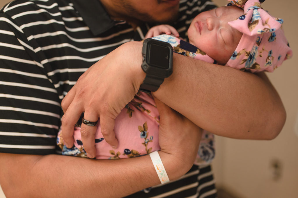 dad holding newborn baby girl in hospital 