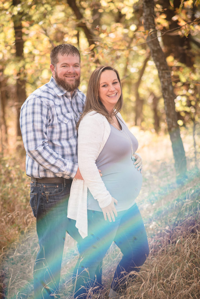 mom and dad maternity photo with lens flare rainbow baby Mustang Oklahoma Pregnancy Photographer